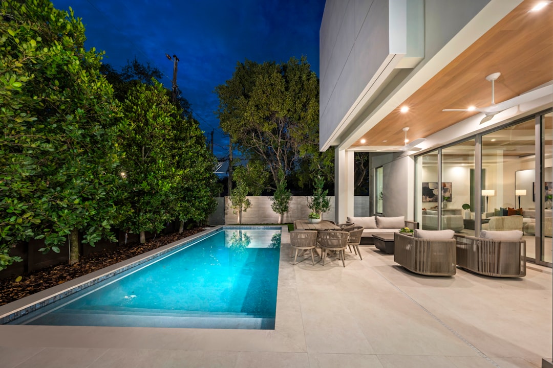 Modern backyard pool area with clear water, surrounded by greenery and contemporary outdoor seating, showcasing Peaster Pools' quality maintenance and cleaning services.